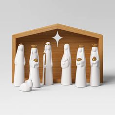 a group of white ceramic figurines standing in front of a wooden box with gold accents