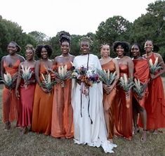 a group of women standing next to each other wearing dresses and holding bouquets in their hands