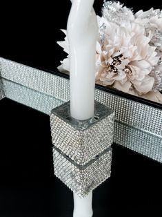 a white candle sitting on top of a table next to a mirror