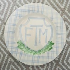 a plate with the letter tm on it sitting on top of a table cloth