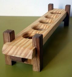 a wooden bench with three holes in the middle on a green table top next to a white wall