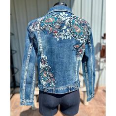 a woman's jean jacket with embroidered flowers on it