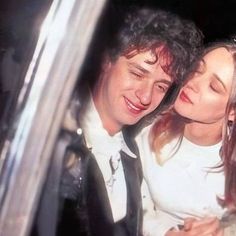 a man and woman sitting next to each other in a car looking at their cell phones