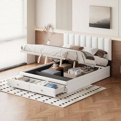 a bed with drawers underneath it on the floor next to a table that has books and magazines in it