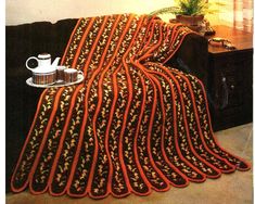 an orange and black blanket sitting on top of a couch next to a coffee pot