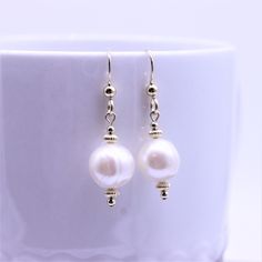 "Simple freshwater pearl earrings are complimented with rich polished gold filled corrugated bead spacers and balls which create a visually pleasing stacked and balanced streamlined design. These simple minimalistic dangle earrings are high polished, and have hammered gold filled French ear wires with decorative beads for a polished finished look. These earrings match all my gold filled necklaces and bracelets so you can coordinate and wear multiple items together. Metal - gold filled findings G Elegant Pearl Beaded Earrings With Pearl Charm, Elegant Beaded Drop Earrings With Pearl Charm, Gold Pearl Drop Beaded Earrings, Elegant Pearl Drop Earrings With Round Beads, Elegant Pearl White Beaded Earrings With Pearl Drop, Pearl Beaded Drop Earrings With Pearl Charm, Pearl Beaded Drop Earrings For Pierced Ears, Gold Beaded Earrings With Pearl Drop For Gifts, Elegant Beaded Earrings With Pearl Charm For Gift