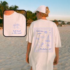 a man wearing a white shirt with blue writing on it and a woman walking along the beach