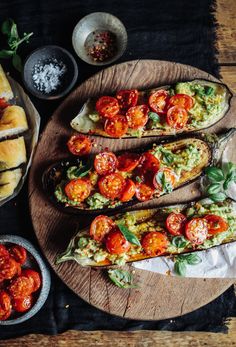 three slices of bread topped with tomatoes and guacamole on a wooden platter