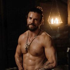 a shirtless man with no shirt standing in front of a fire place and looking at the camera