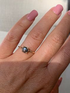 a woman's hand with a ring on it and a pink manicured nail