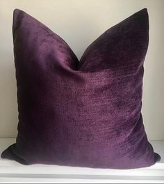 a purple pillow sitting on top of a white shelf