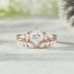 a close up of a diamond ring on a white surface with a pine tree in the background