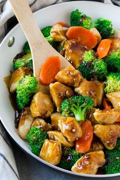 chicken and broccoli stir fry in a pan with a wooden spoon