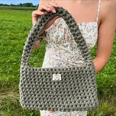 a woman holding a gray crocheted purse