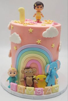 a pink cake with cartoon characters on top and rainbow in the middle, surrounded by clouds