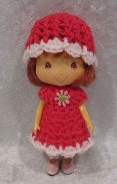 a small doll wearing a red dress and hat