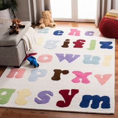 a child's rug with letters and numbers on the floor in front of a window