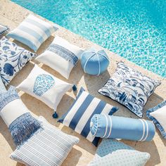 blue and white pillows sitting next to a swimming pool