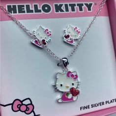 Hello Kitty Jewelry Set Seated Hello Kitty Clutching A Ruby Red Heart Matching Earrings Included! Pendant And Chain Are Crafted From Silver-Plated Brass. Hello Kitty Necklace Features A Delightful Pendant Adorned With Enamel Plating In A Spectrum Of Vibrant Shades, Complemented By A Glimmering Crystal Accent. Approx. 16” Length Silver Cat Design Jewelry For Mother's Day, Pink Jewelry Sets For Valentine's Day, Cute White Hello Kitty Jewelry, Hello Kitty Jewelry For Valentine's Day Gift, Silver Hello Kitty Kawaii Jewelry, Kawaii Silver Hello Kitty Jewelry, Handmade Red Kawaii Jewelry, Kawaii Hello Kitty Silver Jewelry, Playful Handmade Silver Jewelry