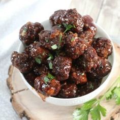 a white bowl filled with meatballs and garnished with parsley