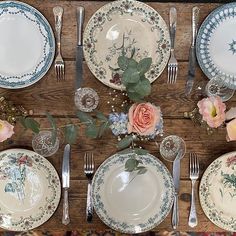 the table is set with plates, silverware and flowers