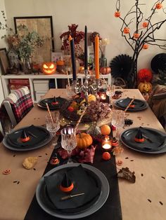 a dining room table set for halloween with candles and pumpkins