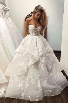 a woman standing in front of a mirror wearing a wedding dress with flowers on it