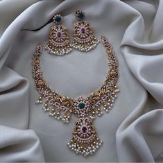 Elevate your bridal ensemble with this exquisite Peacock Matte Gold Finish Haram Necklace and Jhumka Earrings set. This stunning jewelry set is a perfect blend of traditional South Indian craftsmanship and contemporary elegance, designed to make you shine on your special day. ### Features: **Peacock Matte Gold Finish The necklace and earrings boast a luxurious matte gold finish, giving them an antique and regal look, perfect for any Bollywood-inspired wedding. **Intricate Design The set features Luxury Bridal Necklace With Peacock Design, Luxury Kundan Earrings With Peacock Design, Luxury Wedding Chandbalis With Peacock Design, Luxury Temple Necklace With Peacock Design For Wedding, Luxury Peacock Design Necklace In Temple Jewelry Style, Temple Jewelry Sets With Peacock Design For Weddings, Anarkali Sets With Peacock Design For Wedding, Temple Jewelry Peacock Design Jhumkas For Wedding, Wedding Kundan Chandbali Necklace With Peacock Design