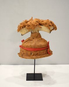 a hat made out of palm leaves on a black stand