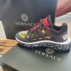 Futuristic Design That Fuses The House’s Codes With Lightweight Shock-Absorbing Greca Rubber And Eva Outsoles. The Trimmed Mesh Upper Is Distinguished By A Hand-Knotted Rope Construction. The Insole Features Dynamic, Screen-Printed Mercury Lettering, And The Tongue Is Embellished With A Printed Versace Logo And A Greca Jacquard Ribbon Pull Tab. Luxury Black Sneakers With Logo, Luxury Black Sneakers With Logo Print, Designer Black Sneakers With Logo Print, Black Running Sneakers With Logo, Designer Sports Sneakers With Red Sole, Designer Black Custom Sneakers With Logo Print, Designer Sneakers With Red Sole For Sports, Luxury Low-top Sneakers For Running, Designer Black Custom Sneakers With Red Sole