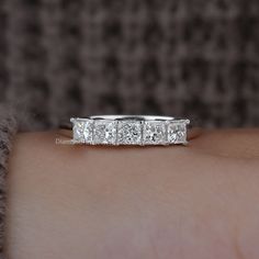 a woman's hand with a wedding band on it and five diamonds in the middle