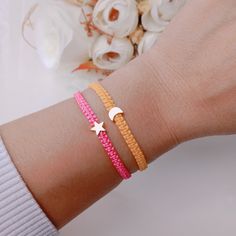 a woman's arm wearing two bracelets with stars and moon charms on it