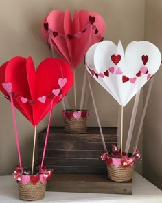 three heart shaped paper balloons sitting on top of a table