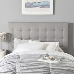 a bed with white pillows and gray headboard