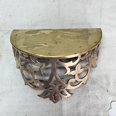 a gold and silver shelf on a white wall next to a flowery planter