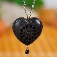 Barro negro or black clay is a distinctly Oaxacan crafting tradition that dates back centuries. Mariana Barranco in Mexico creates this gorgeous necklace with a heart-shaped barro negro pendant incised with small petal motifs. The pendant graces a sterling silver rolo chain stationed with glossy black crystal beads. Traditional Handmade Heart Necklaces, Artisan Carved Black Necklace, Artisan Black Carved Necklace, Artisan Black Carved Jewelry, Artisan Black Pendant Jewelry, Handmade Black Heart-shaped Jewelry, Artisan Heart Beads Pendant Necklace, Artisan Black Jewelry Gift, Bohemian Black Carved Necklace