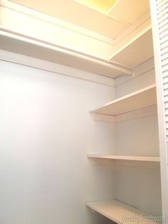 an empty walk in closet with white shelving and no door for the toilet or sink