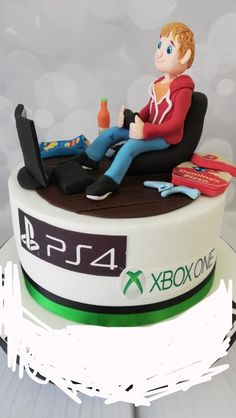 a birthday cake with a boy sitting on top of it and holding a game controller