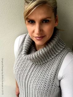 a woman with blonde hair wearing a gray knitted cowl neck sweater and scarf