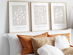 three framed art prints on the wall above a bed with pillows and throw pillows in front of them