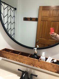 a woman taking a selfie in front of a mirror with her cell phone and soap