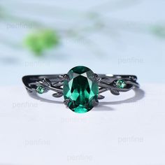 an oval cut green gemstone ring on top of a white surface