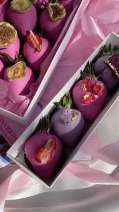 two boxes filled with chocolate covered strawberries on top of a pink table cloth next to each other