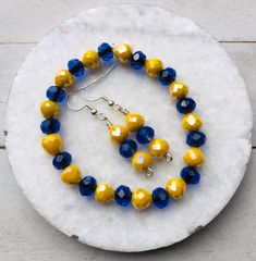 Bright yellow and blue stretch bracelet with matching earrings. This stretch bracelet set is made with faceted 8mm glass beads with strong elastic cord and silver plated ear wires. This blue and yellow jewelry set is perfect for representing your team colors.  MY ENTIRE COLLECTION https://www.etsy.com/shop/MiksJewelryShop Please message me with any questions you may have. - Mikaila Don't forget to FAVORITE ♥️ YOUR favorite items & also my shop so you can easily find them again. Bracelet Game, Team Bracelets, Blue Game, Blue Beaded Bracelets, Yellow Jewelry, Boho Chic Jewelry, Stackable Bracelets, Bracelets For Women, School Colors