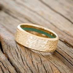 a wooden ring with a green stone in the center on a wood surface, close up