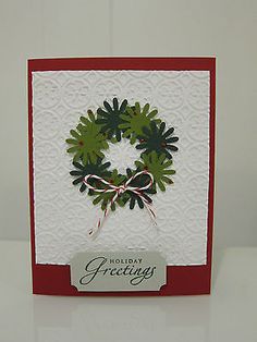 a christmas card with a green wreath on the front and red trimming around it