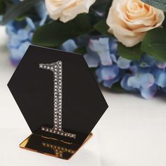 a diamond number one on top of a black stand next to blue and white flowers