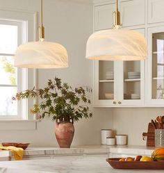 two hanging lights above a kitchen island with fruit on it