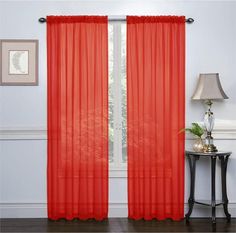 a red curtain hanging on the side of a wall next to a table with a lamp