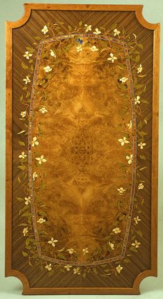 an ornate wooden frame with flowers and leaves on the border, inlaid to wood